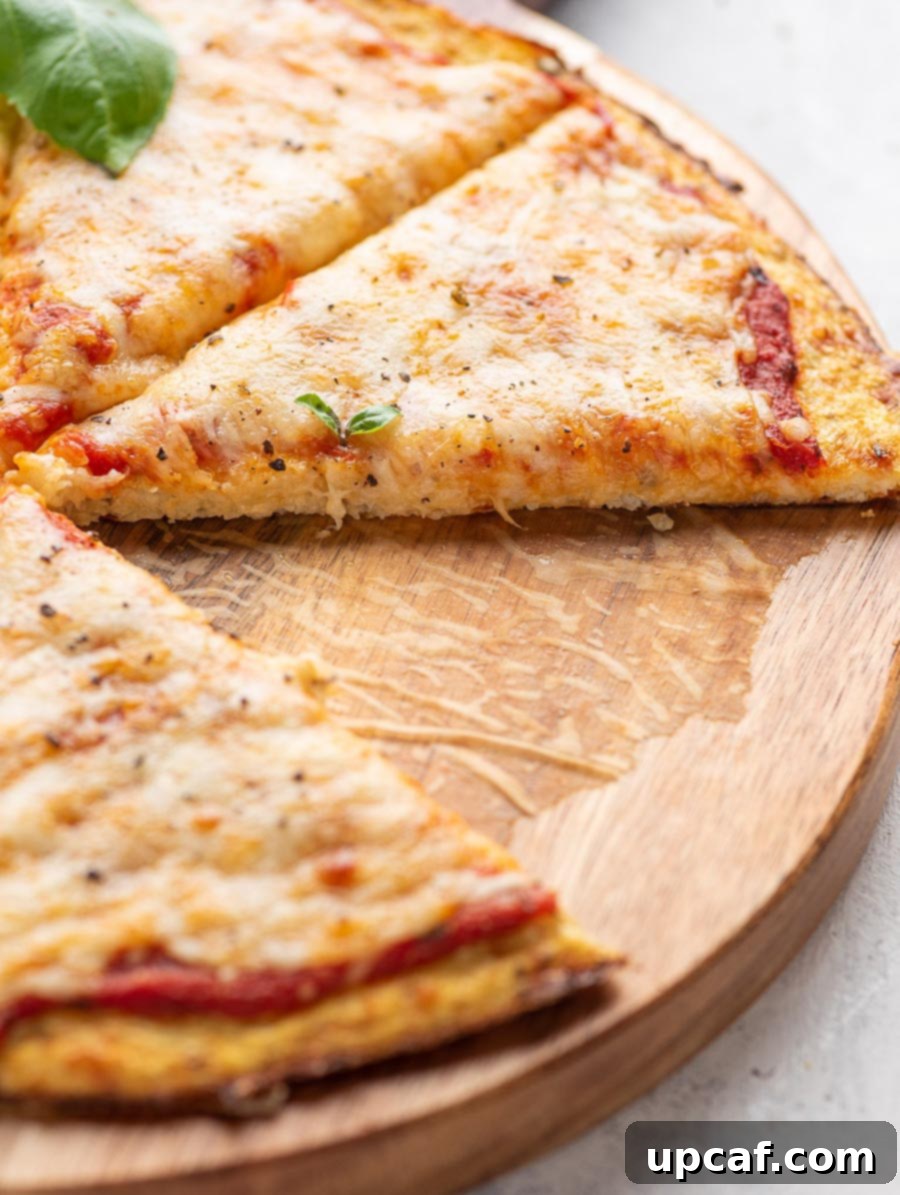 A close-up shot of a slice of cauliflower pizza, showcasing the crispy crust, melted cheese, and fresh basil.