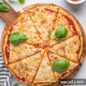 Top-down shot of a freshly baked cauliflower pizza with basil leaves on top, indicating its delicious appeal.