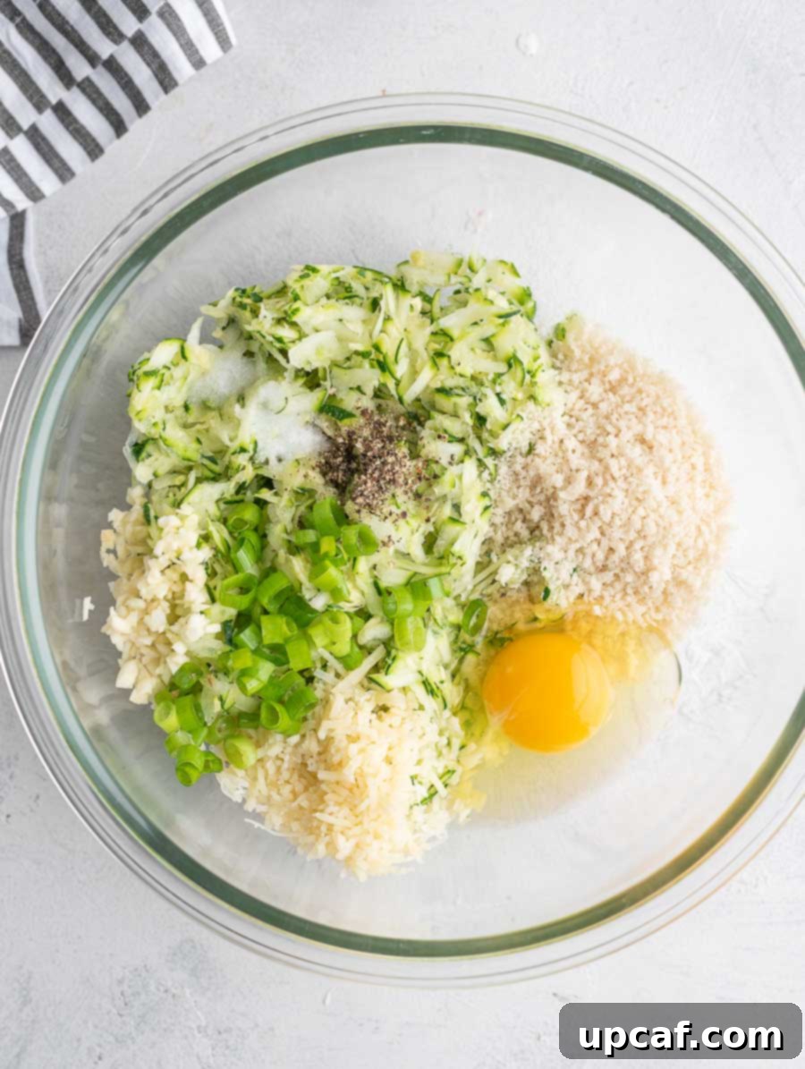 Crispy Zucchini Pancakes 5 Various ingredients for zucchini fritters gathered in a bowl, ready to be mixed together.