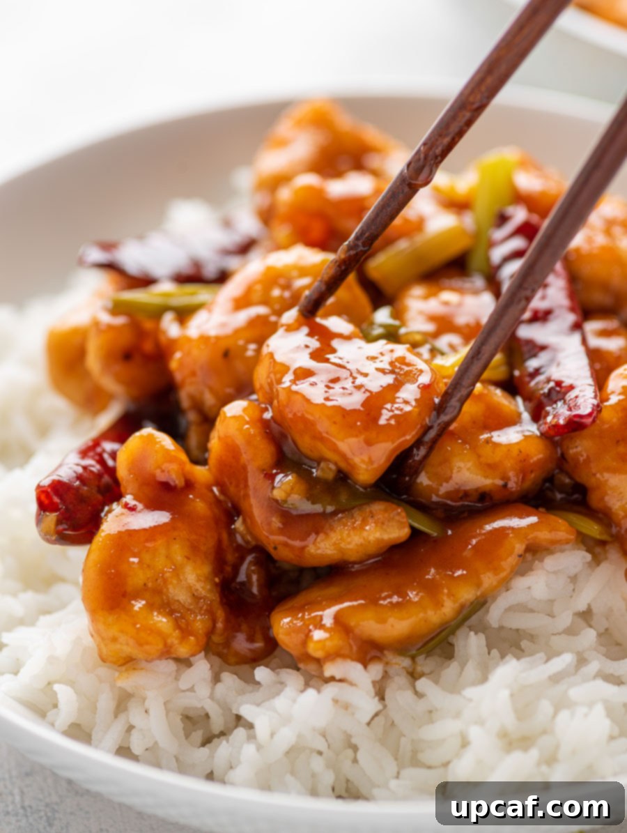 Quick Sticky Mongolian Chicken 10 chop stick holding onto a piece of mongolian chicken