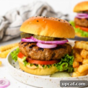 A homemade burger on a plate with toppings and fries.