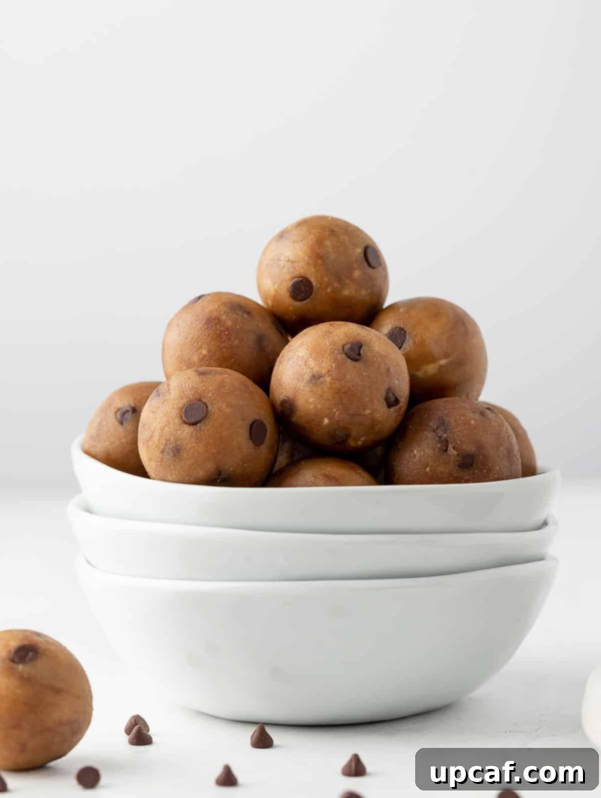 Delicious protein cookie dough balls neatly arranged in a white ceramic bowl, showcasing their irresistible texture and mini chocolate chips.