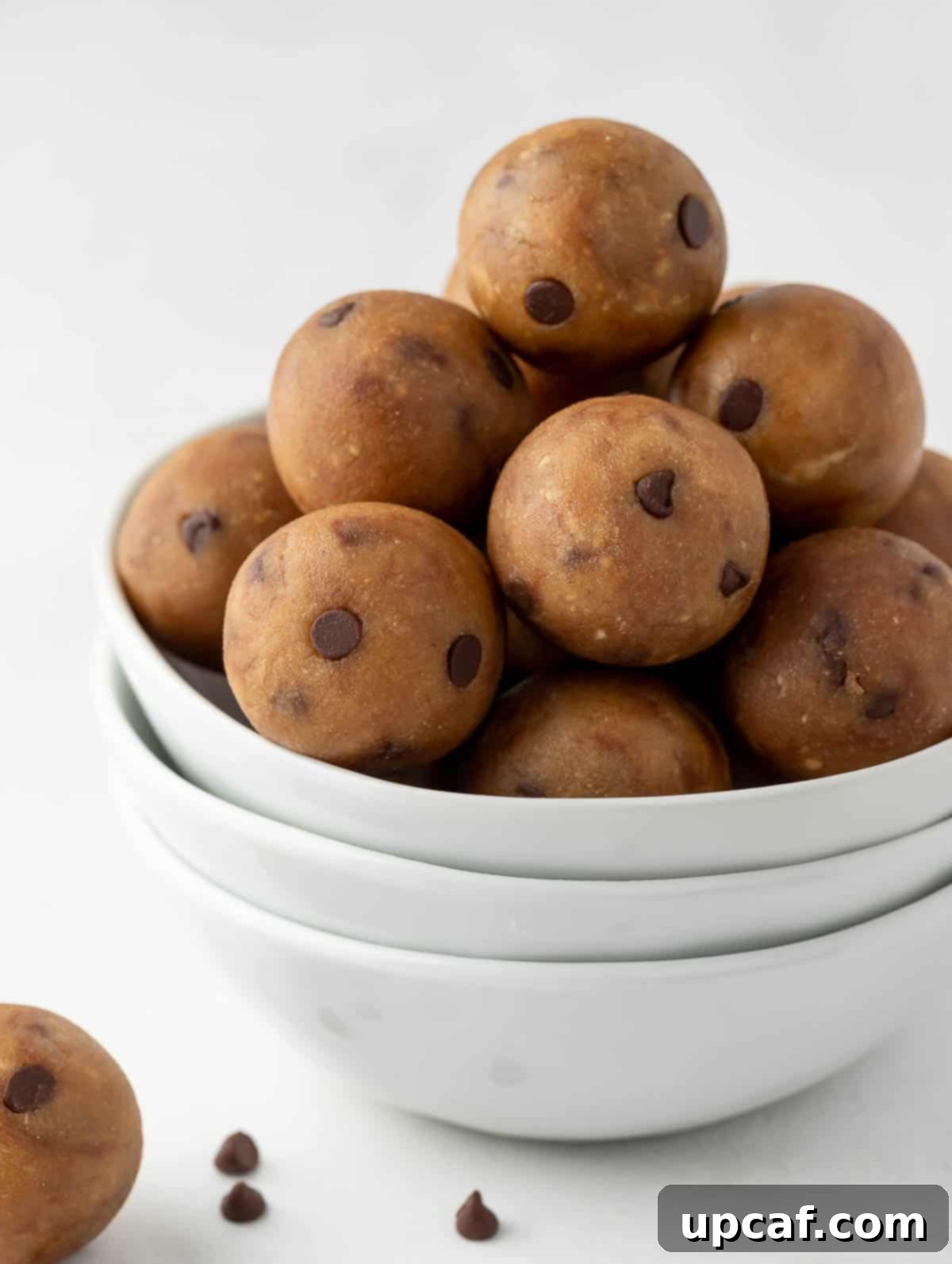 A beautiful close-up side shot of the delicious protein cookie dough balls in a white bowl, highlighting their perfect round shape and texture.