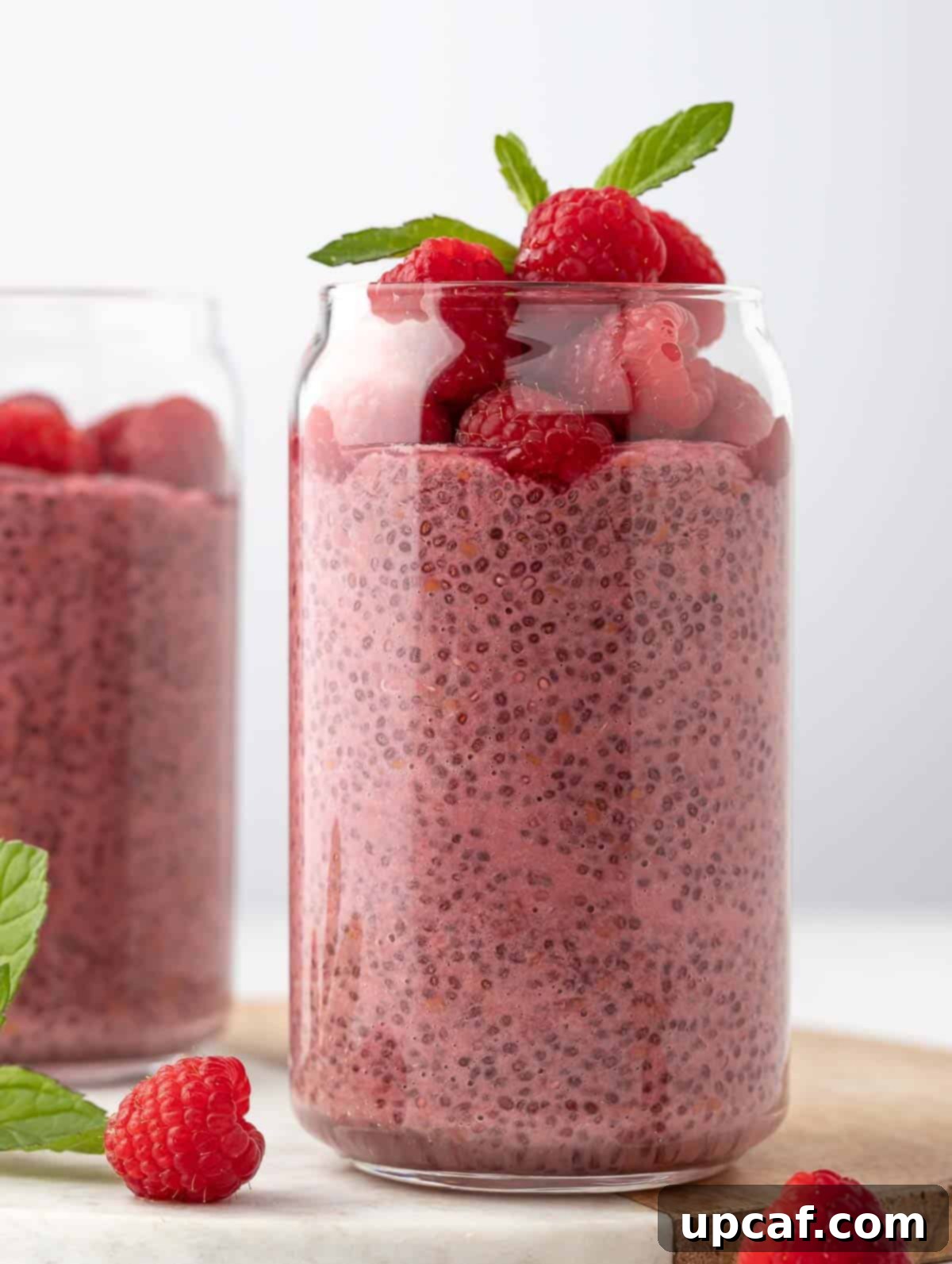 Vibrant Raspberry Chia Pudding 2 Close-up shot of Raspberry Protein Chia Pudding, beautifully topped with fresh raspberries and a sprig of mint, ready to be enjoyed.