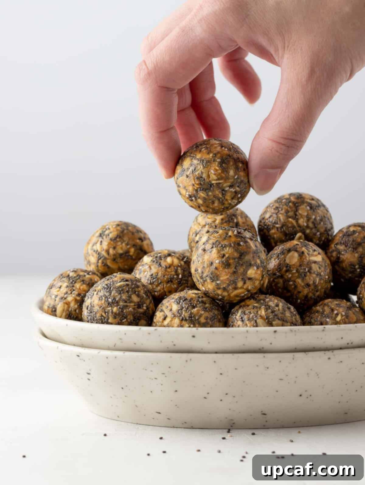 Vanilla Protein Power Bites 8 Hand reaching for a vanilla protein energy ball, showing its perfect size and texture