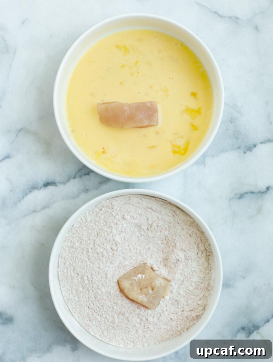 Chicken pieces being dredged in flour and egg wash mixtures for coating.