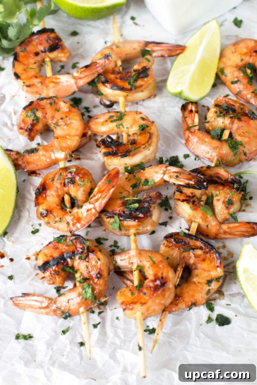 Agave Cilantro Shrimp Skewers on parchment paper with lime and cilantro