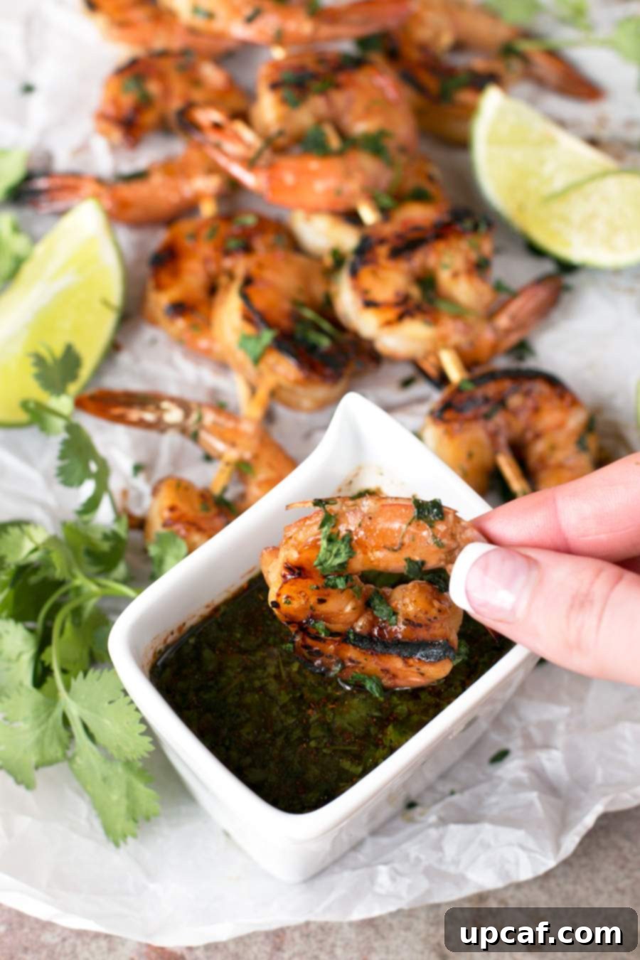 Someone dipping Agave Cilantro Shrimp Skewers into spicy dipping sauce.