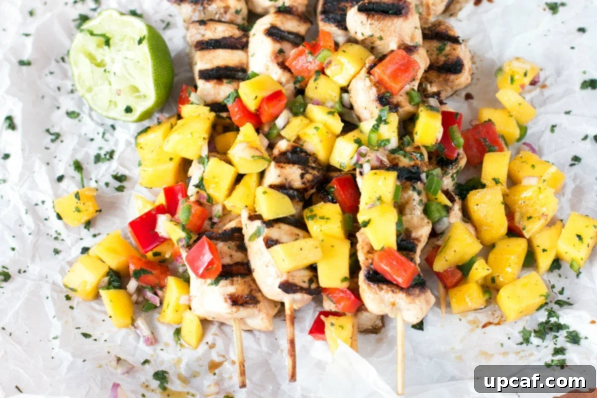 Overhead picture of mango chicken on kabobs with mango salsa and lime