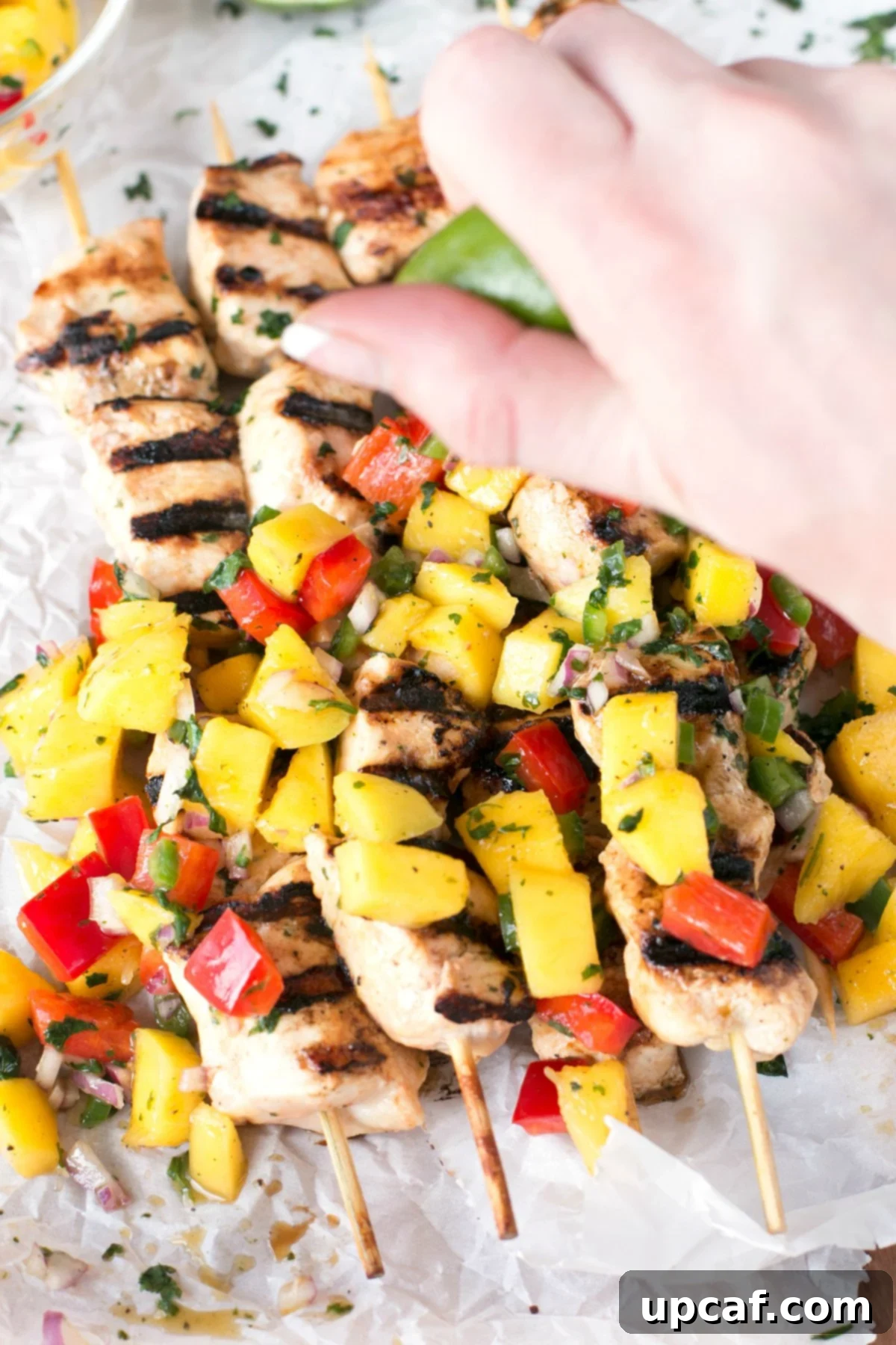 Mango chicken topped with mango salsa and a hand squeezing fresh lime on top