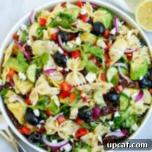 Lemon herb Mediterranean salad served in a white bowl, with a side of lemon