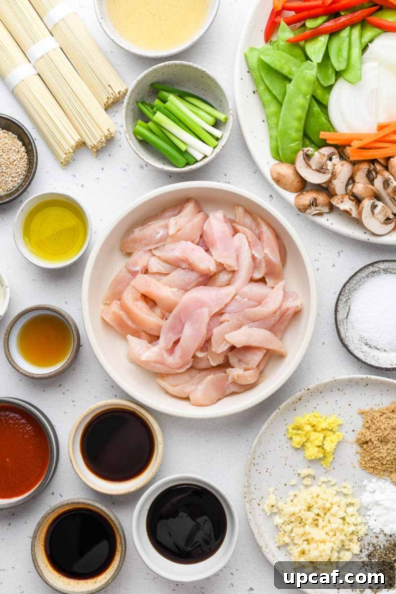 All fresh ingredients for chicken lo mein laid out on a cutting board.