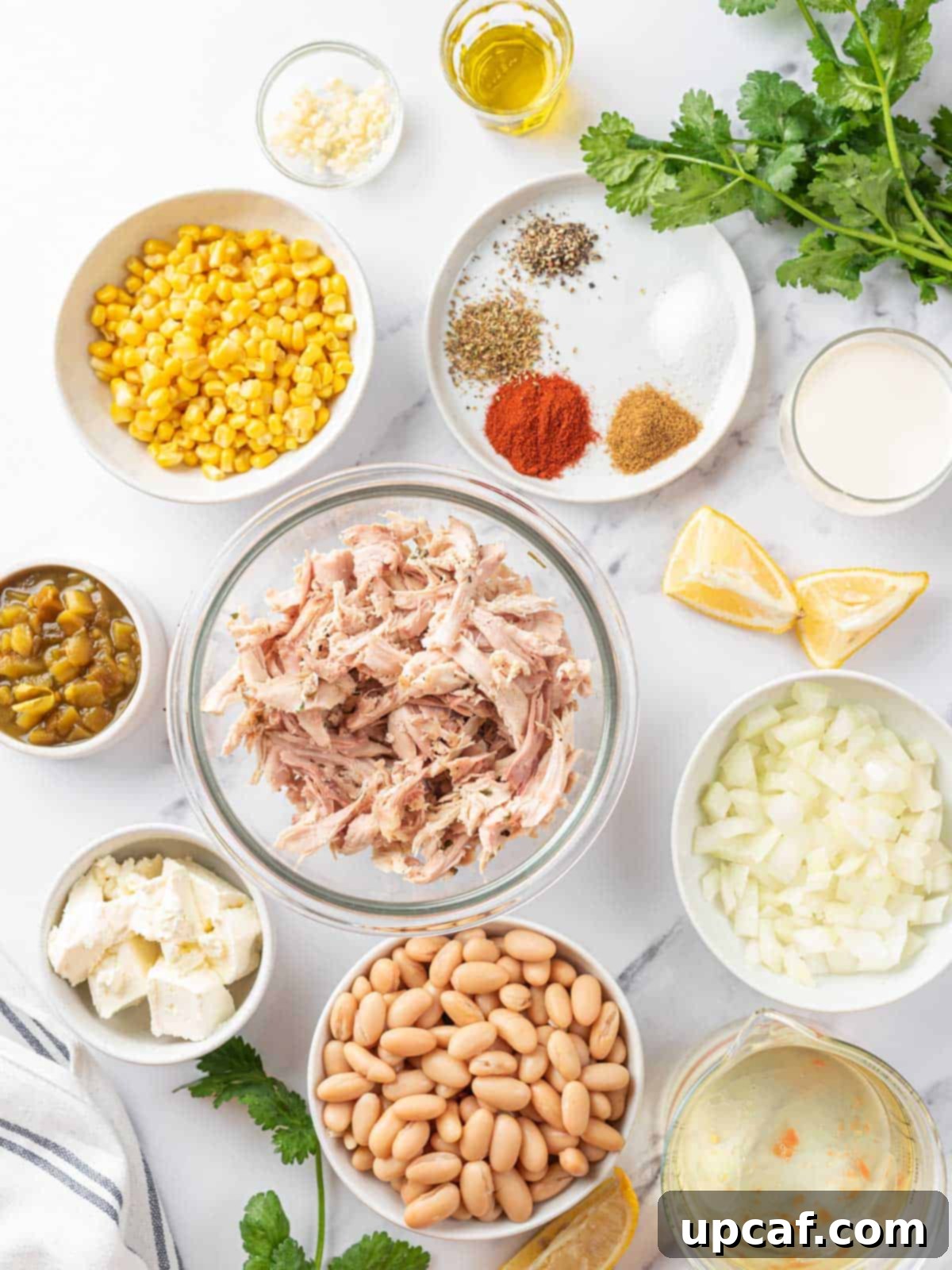 A vibrant display of fresh ingredients for white chicken chili, including spices, chicken, and vegetables.
