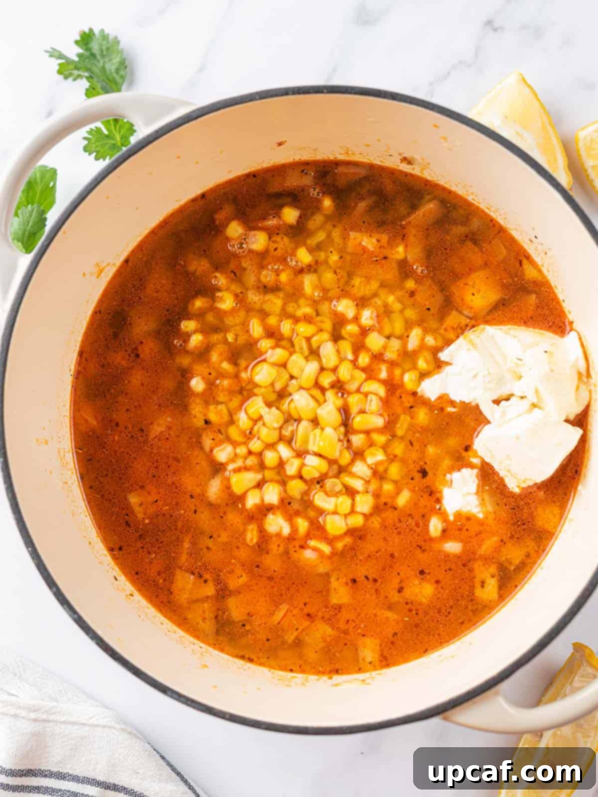A pot filled with the creamy white chili base, featuring beans, corn, and green chilies, before the shredded chicken is added.