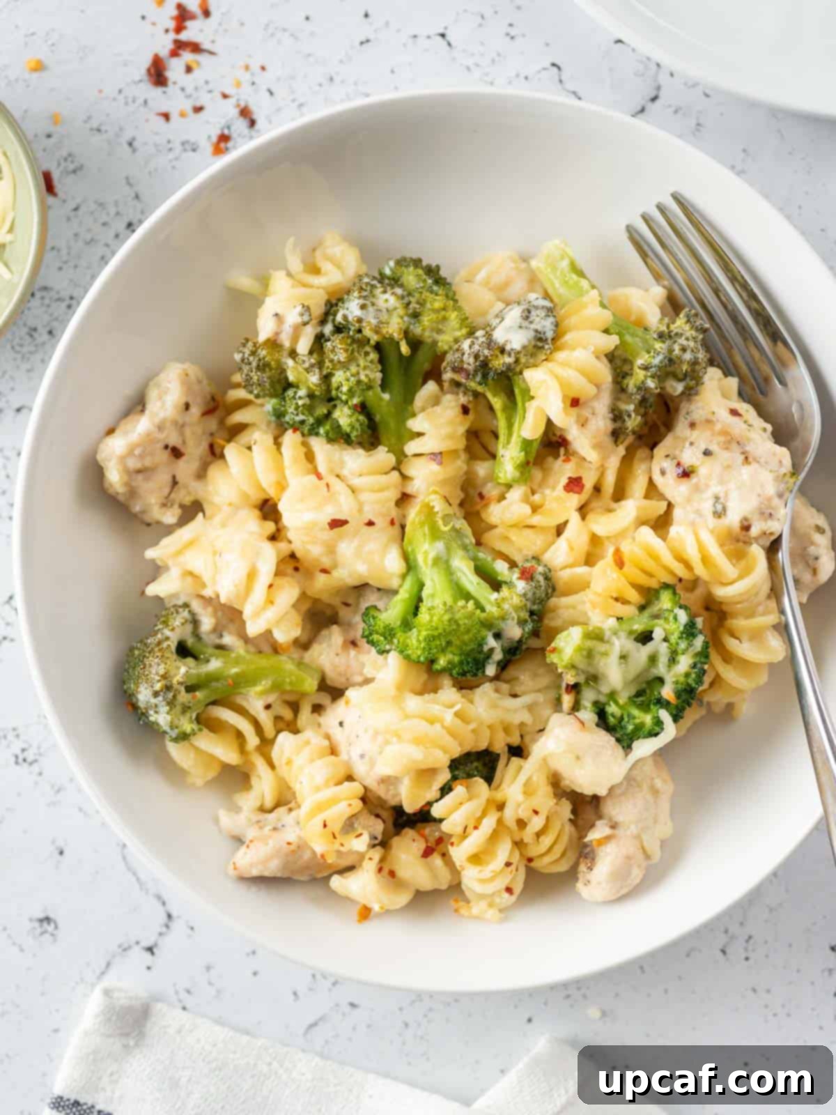 a fork paid on the side of the pasta and broccoli dish on a plate
