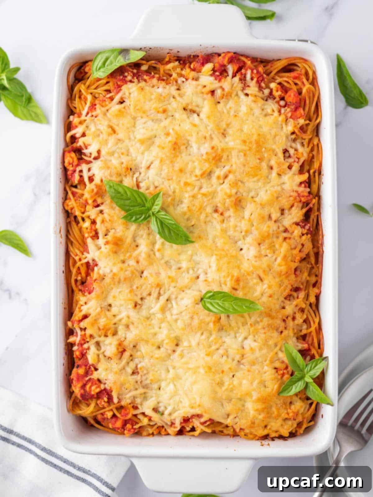 A perfectly baked spaghetti pasta casserole, garnished with fresh basil leaves, ready to be served.