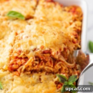 Spatula lifting out a portion of the baked spaghetti, showing cheesy layers.