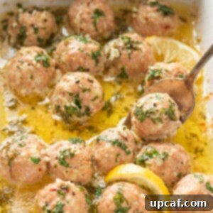Garlic Butter Turkey Meatballs in a baking dish with a spoon scooping one.