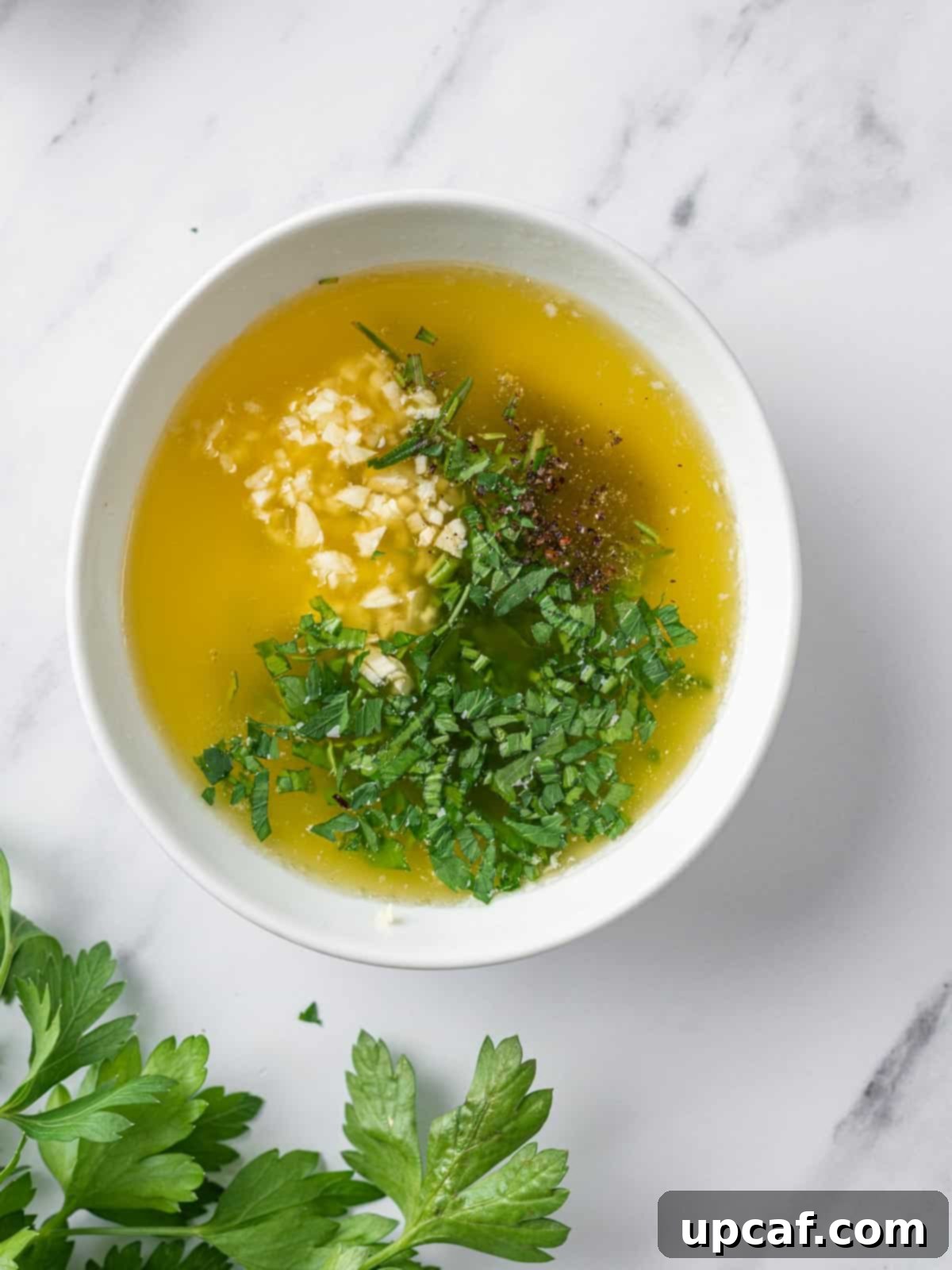 Melted butter infused with fresh herbs and minced garlic, ready to coat the chicken.