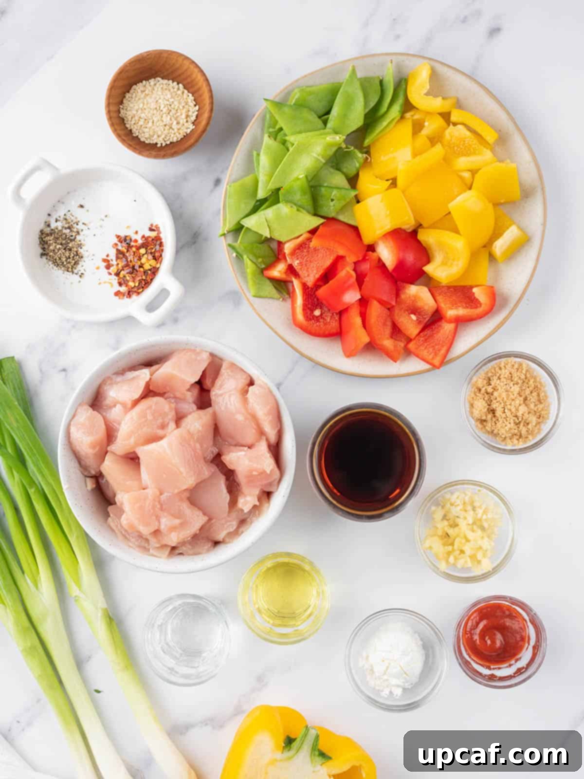 Various ingredients for Szechuan chicken including cubed chicken, bell peppers, snow peas, and sauce components.