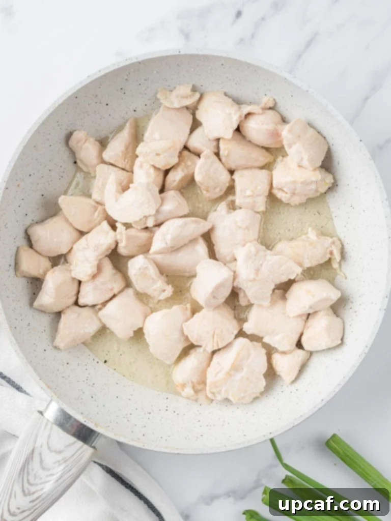 Sautéed cubed chicken in a skillet, browning nicely.