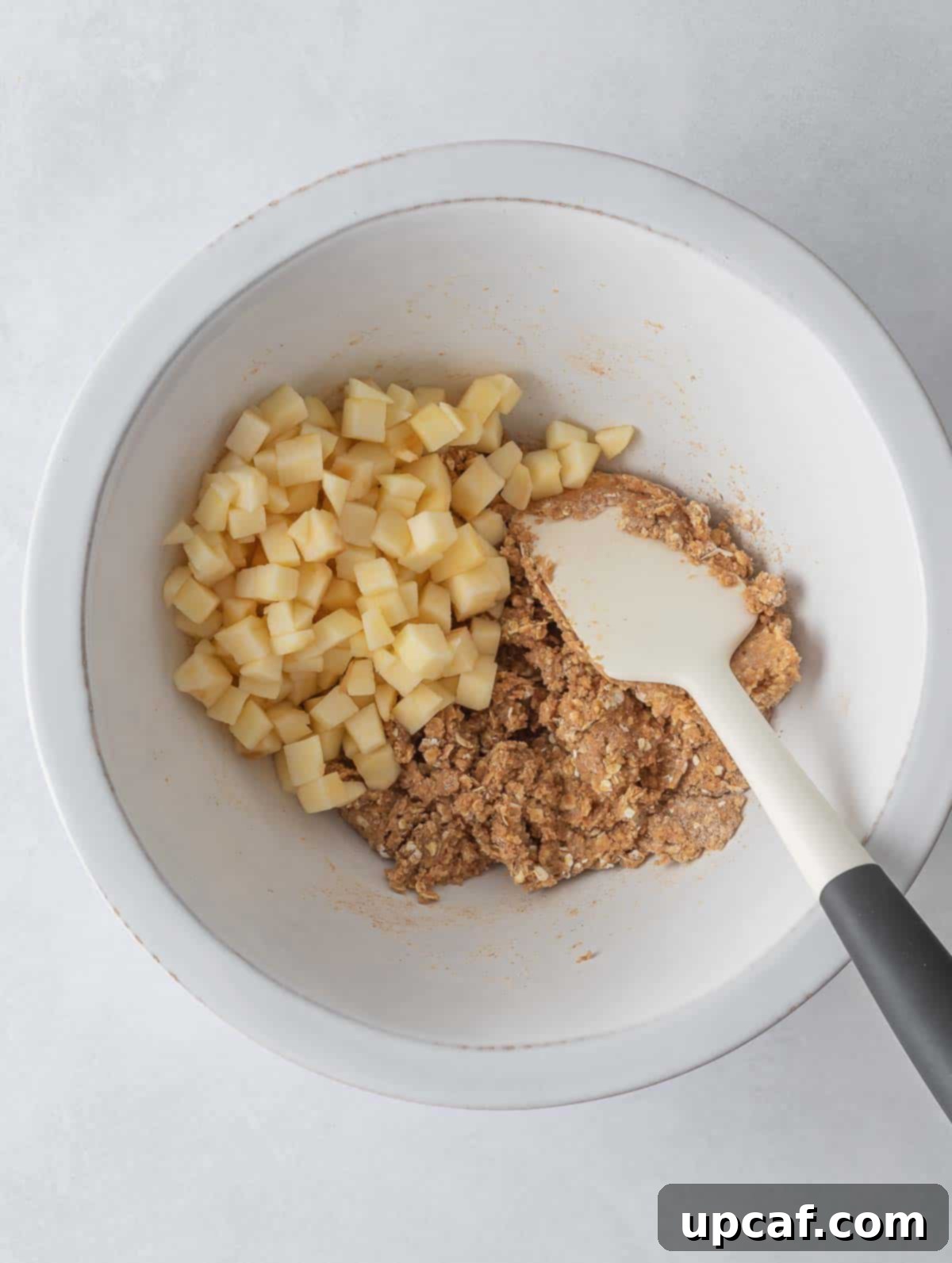 Cozy Apple Pie Cinnamon Oat Cookies 5 Diced apples added to the cookie dough in a mixing bowl.