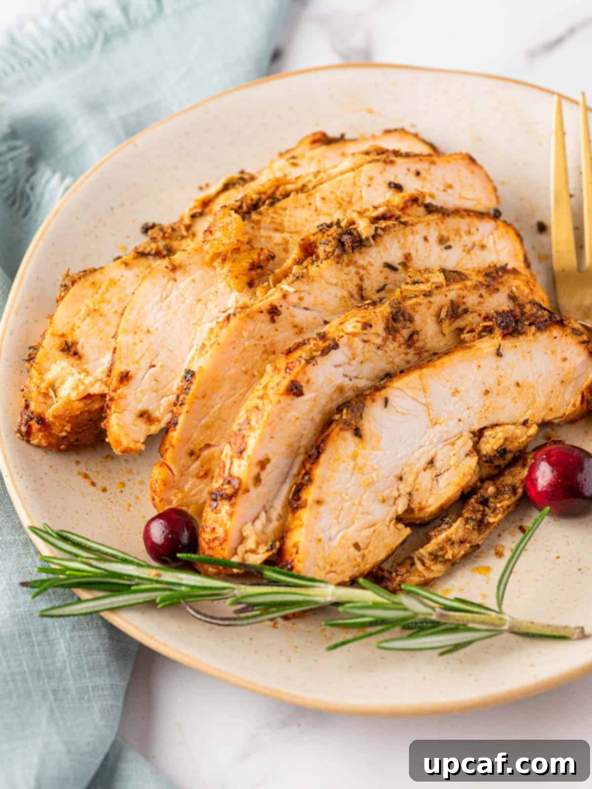 Juicy Roasted Turkey Breast 8 sliced pieces of oven roasted turkey breast on a plate, garnished with fresh herbs