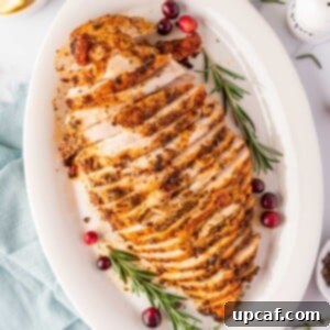 Juicy Roasted Turkey Breast 9 overhead shot of sliced turkey breast on a white plate with cranberry and rosemary stalks