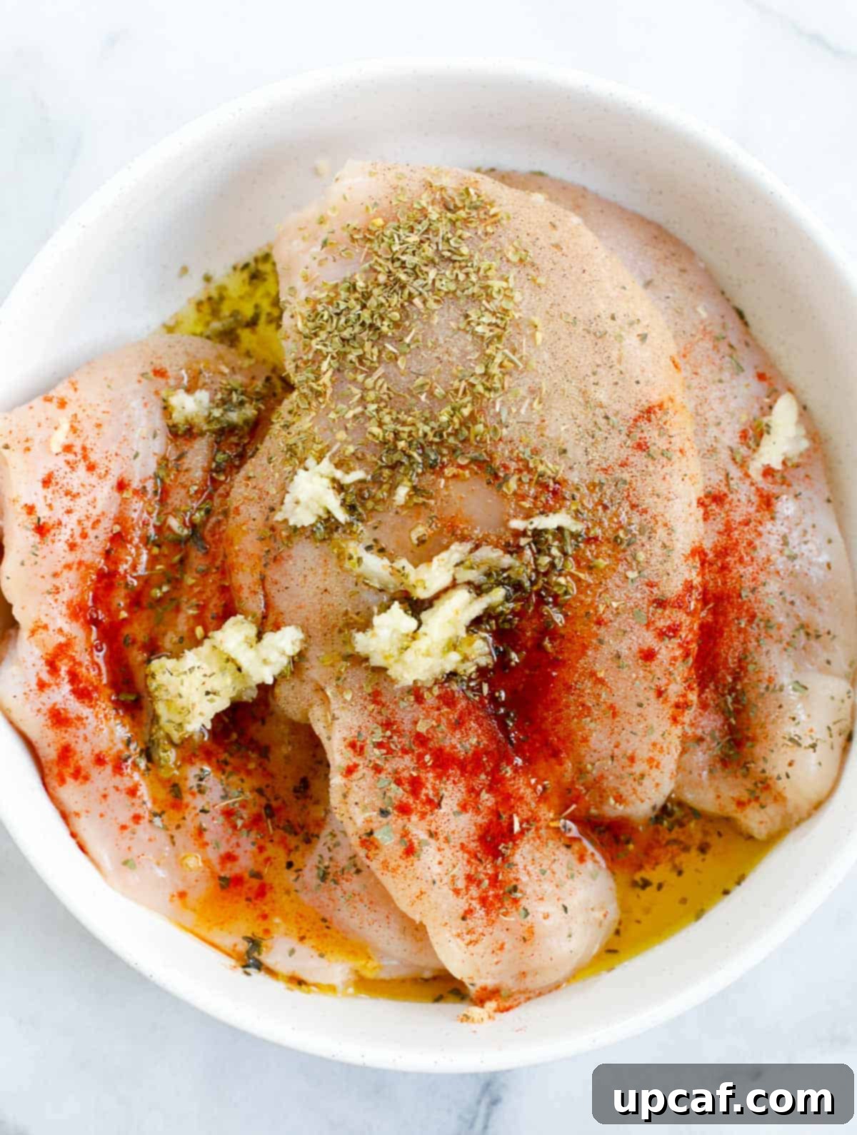 Sheet Pan Mediterranean Chicken Bake 4 Chicken breast seasoned in a bowl, ready for cooking.