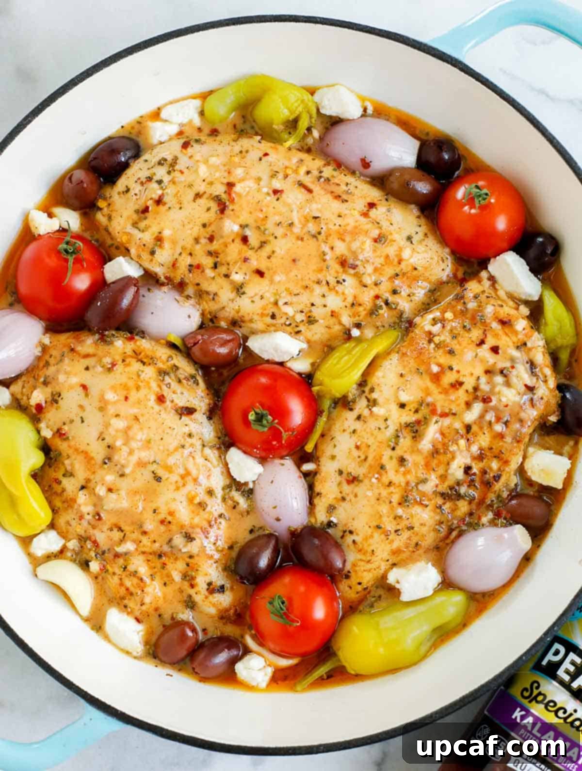 Sheet Pan Mediterranean Chicken Bake 6 A pan filled with chicken, vegetables, and olives, coated in marinade and ready for baking.