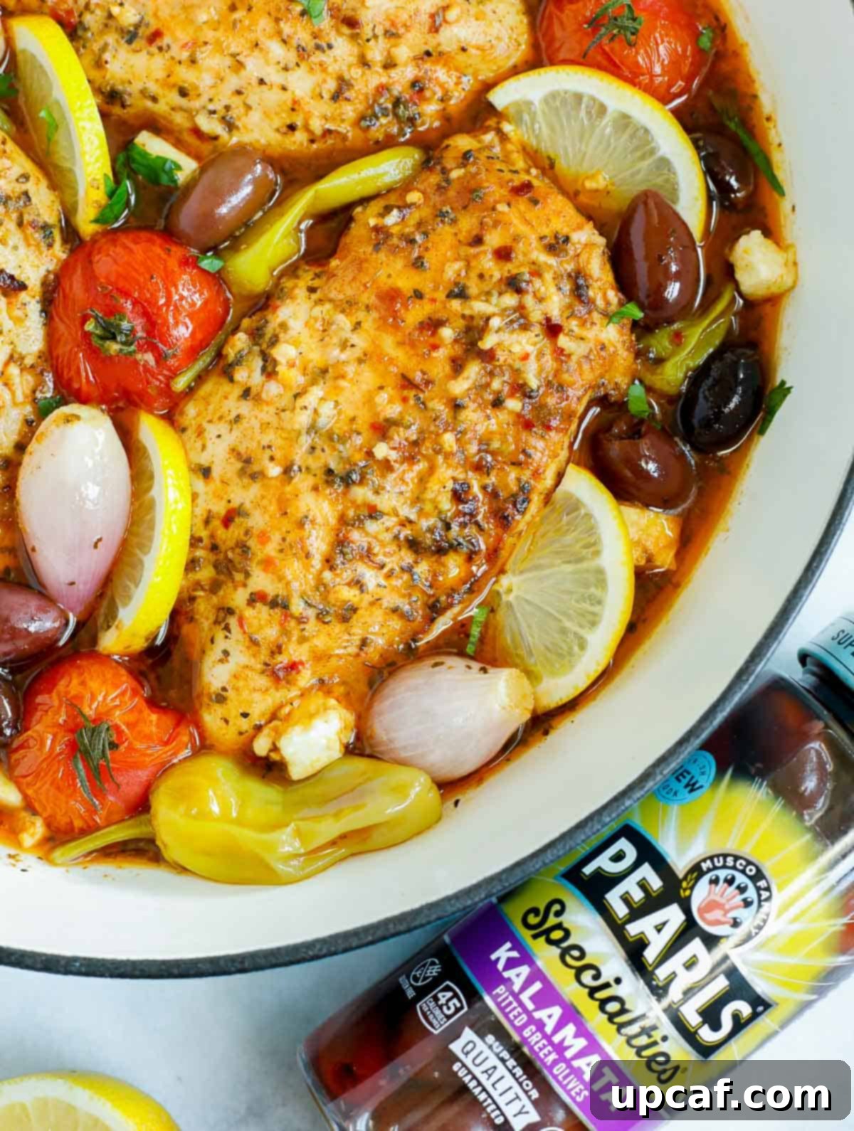 Sheet Pan Mediterranean Chicken Bake 7 Close-up of baked Greek chicken next to a jar of Kalamata olives, highlighting the fresh ingredients.