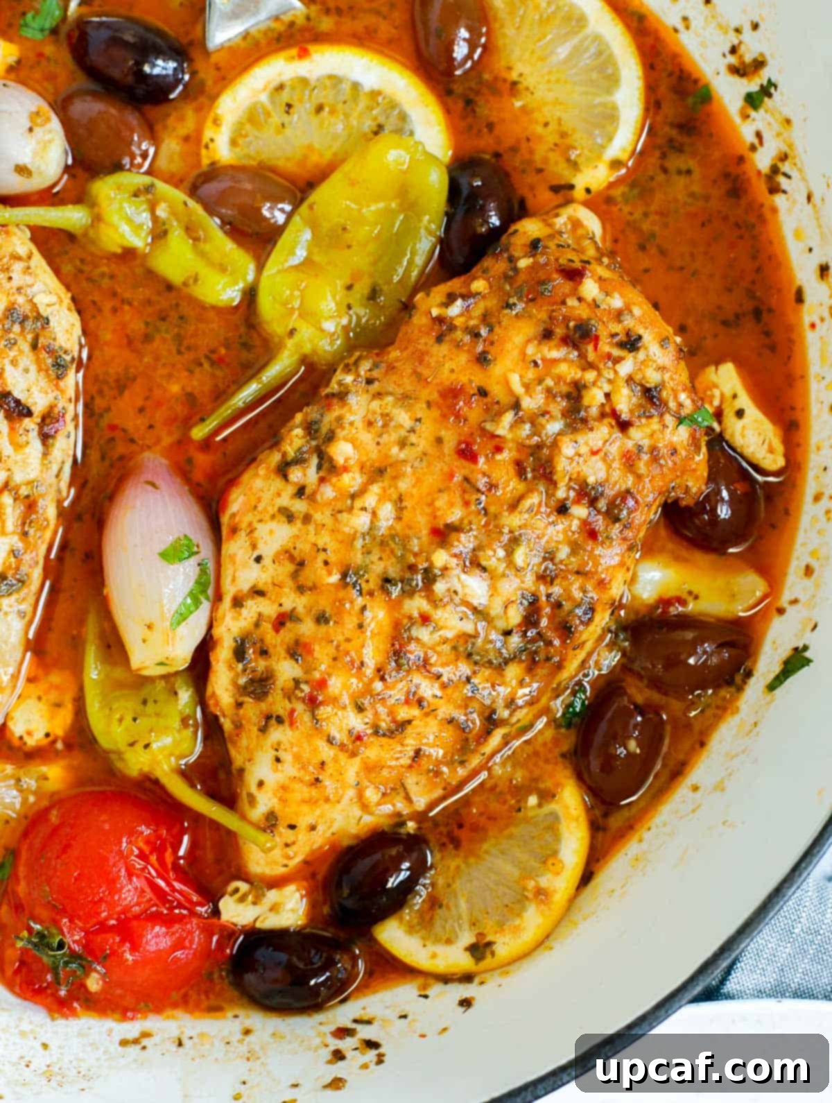 Sheet Pan Mediterranean Chicken Bake 8 Close up of a pan of oven baked Greek chicken breasts, richly seasoned and surrounded by vegetables.
