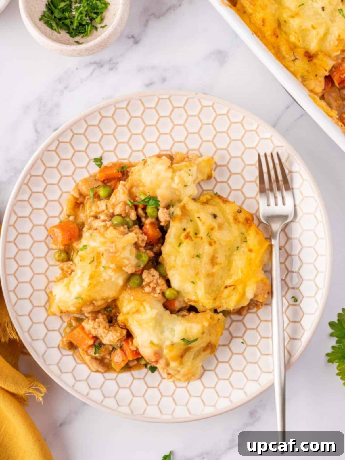 A slice of Chicken Shepherd's Pie served on a white plate, showing the distinct layers of mashed potato and savory filling.