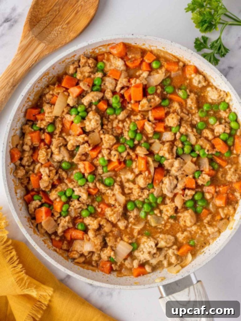 The finished chicken and vegetable filling ready in a skillet before transferring to a baking dish.