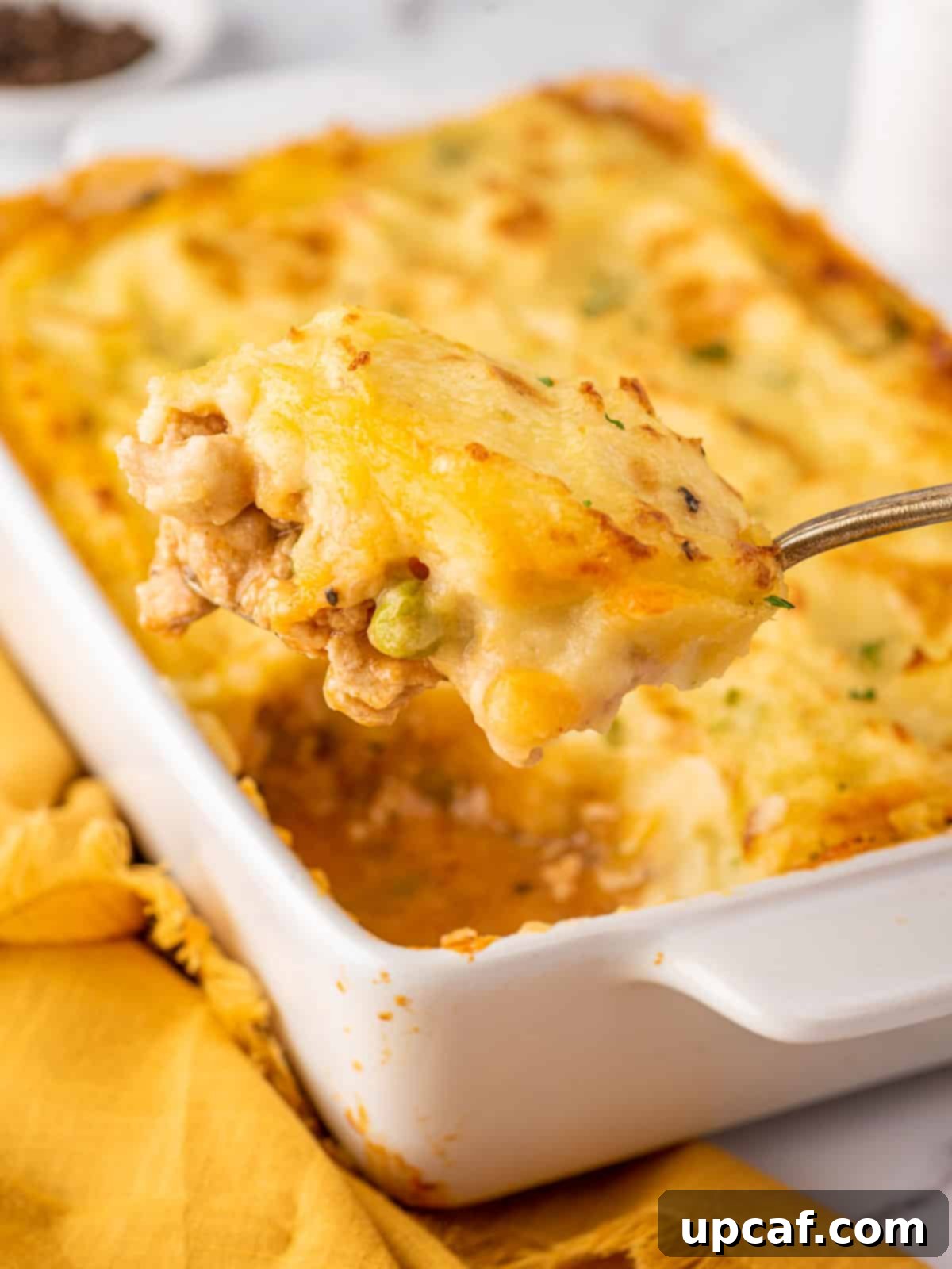 A serving spoon scooping out a generous portion of Chicken Shepherd's Pie, showing the layers of mashed potato and savory filling.