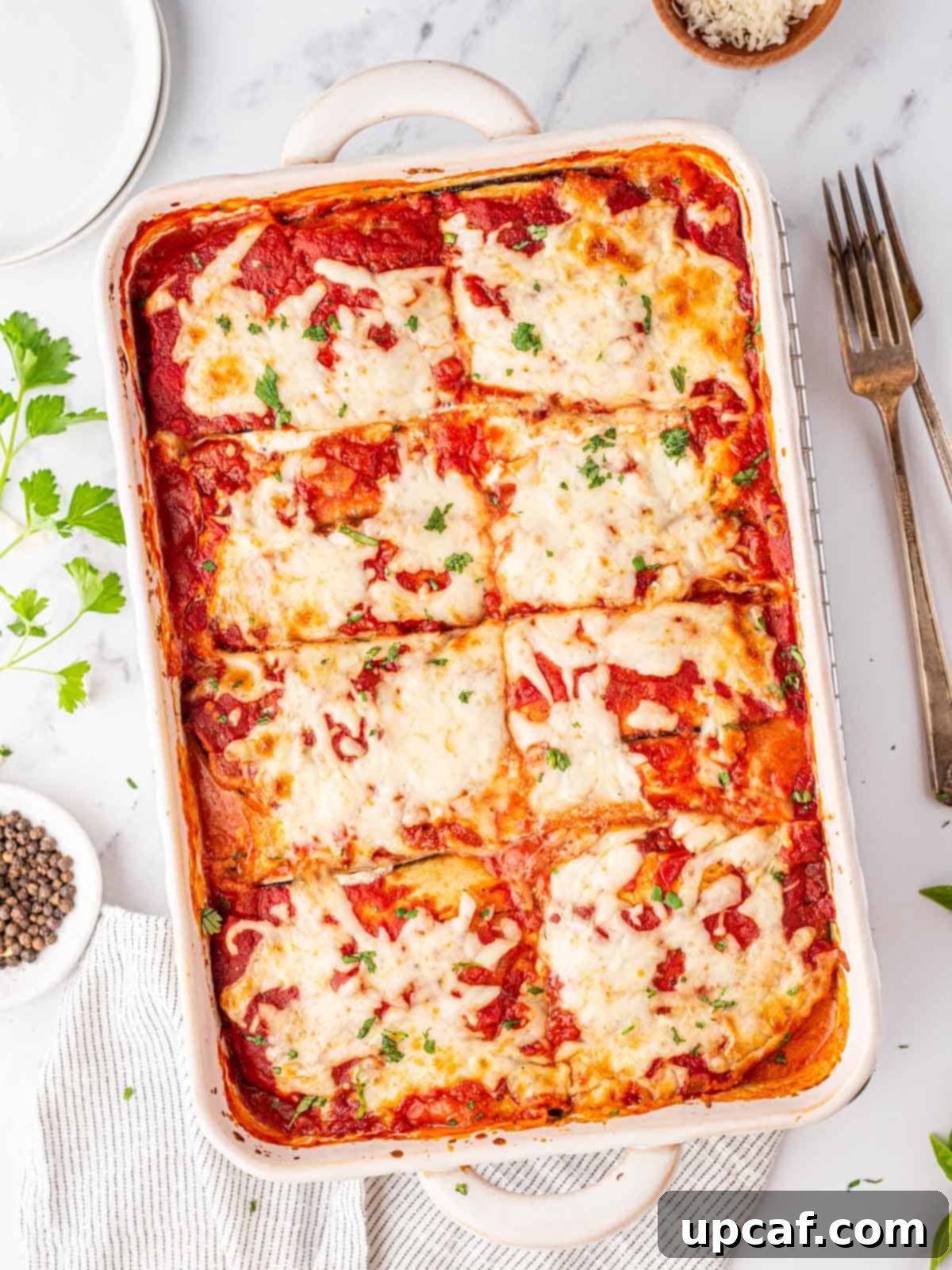 A beautiful top-down shot of a golden-brown Eggplant Parmesan Lasagna in a baking dish, with steam subtly rising, ready to be served.