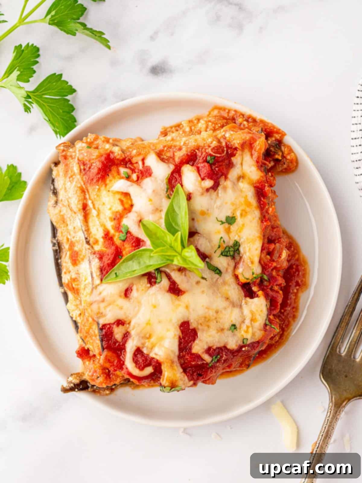 A perfectly portioned slice of Eggplant Parmesan Lasagna on a white plate, showcasing its layers and rich textures.