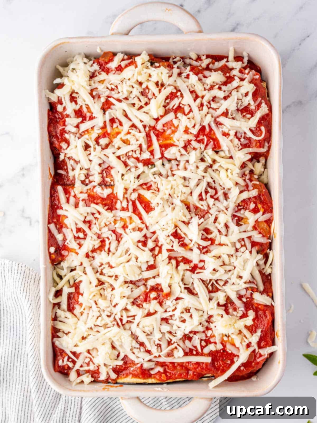 A beautifully assembled eggplant parmesan lasagna, topped with a generous layer of mozzarella cheese, ready to be baked.