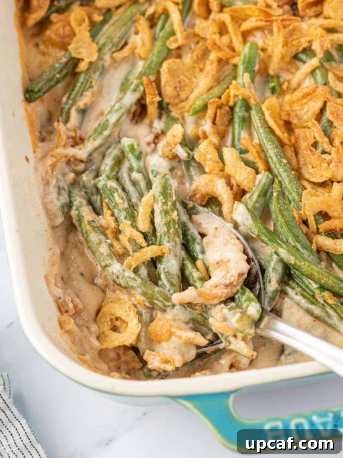 Cheesy Green Bean Casserole in a baking dish with spoon in it
