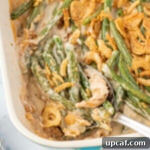 Cheesy Green Bean Casserole in a baking dish with spoon in it