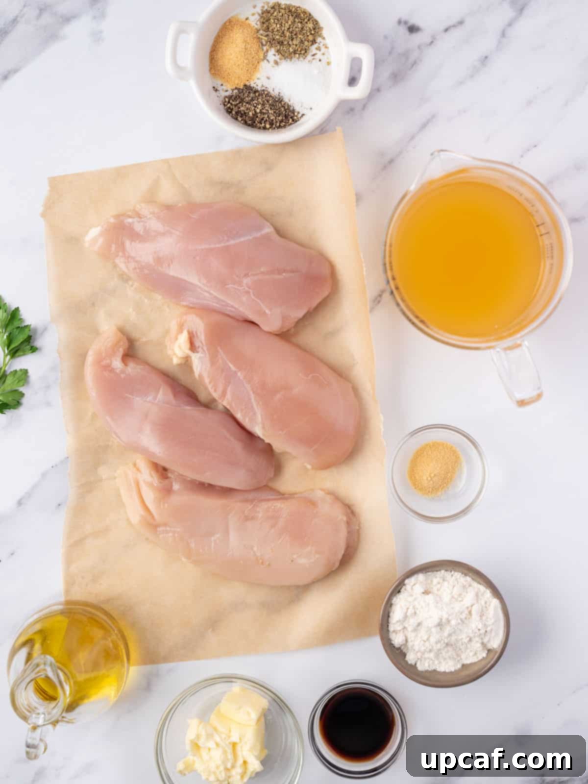 Effortless Chicken and Savory Gravy 3 A display of fresh ingredients laid out for making chicken and gravy, including chicken breasts, herbs, and broth.