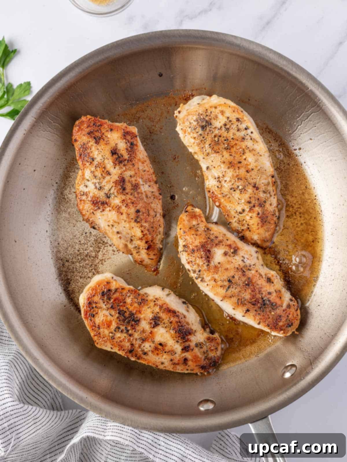 Effortless Chicken and Savory Gravy 4 Chicken breasts being seared to a golden-brown perfection in a large skillet.