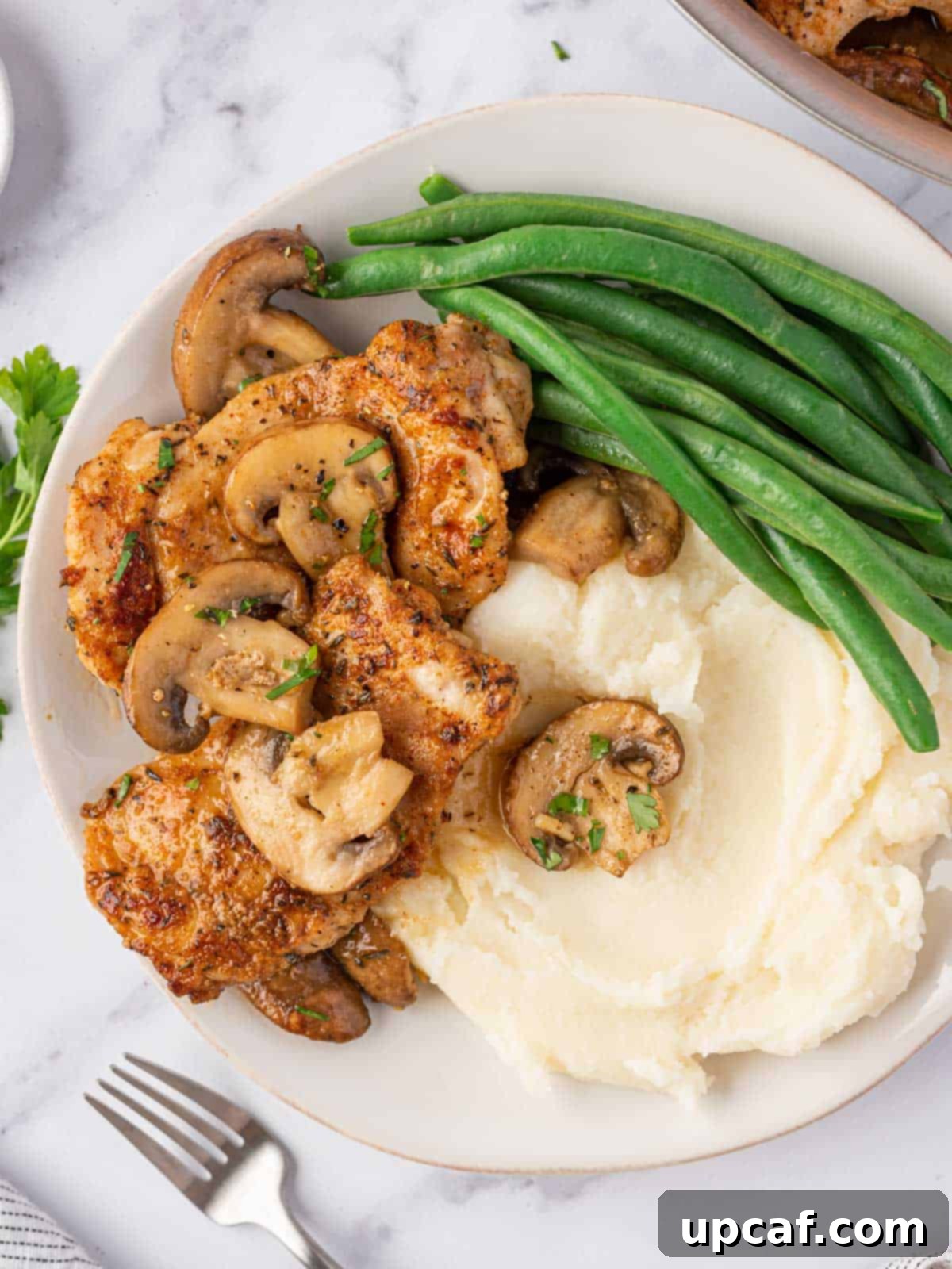 Flavorful Garlic Mushroom Chicken Thighs 2 A beautifully plated dish of garlic mushroom chicken thighs, served alongside creamy mashed potatoes and vibrant green beans.