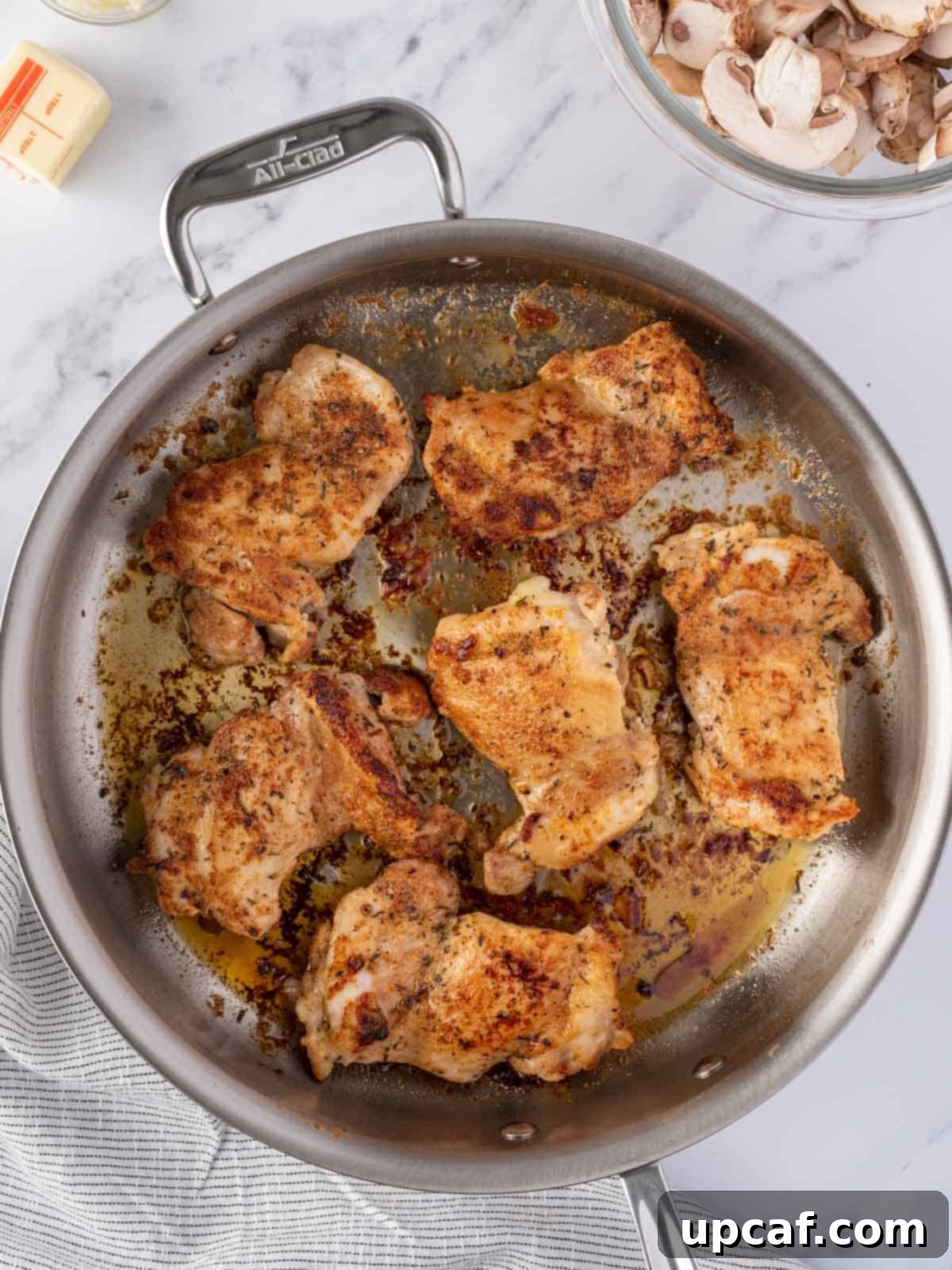 Flavorful Garlic Mushroom Chicken Thighs 5 Close-up of golden-brown, pan-seared chicken thighs cooking in a hot skillet, creating a flavorful crust.