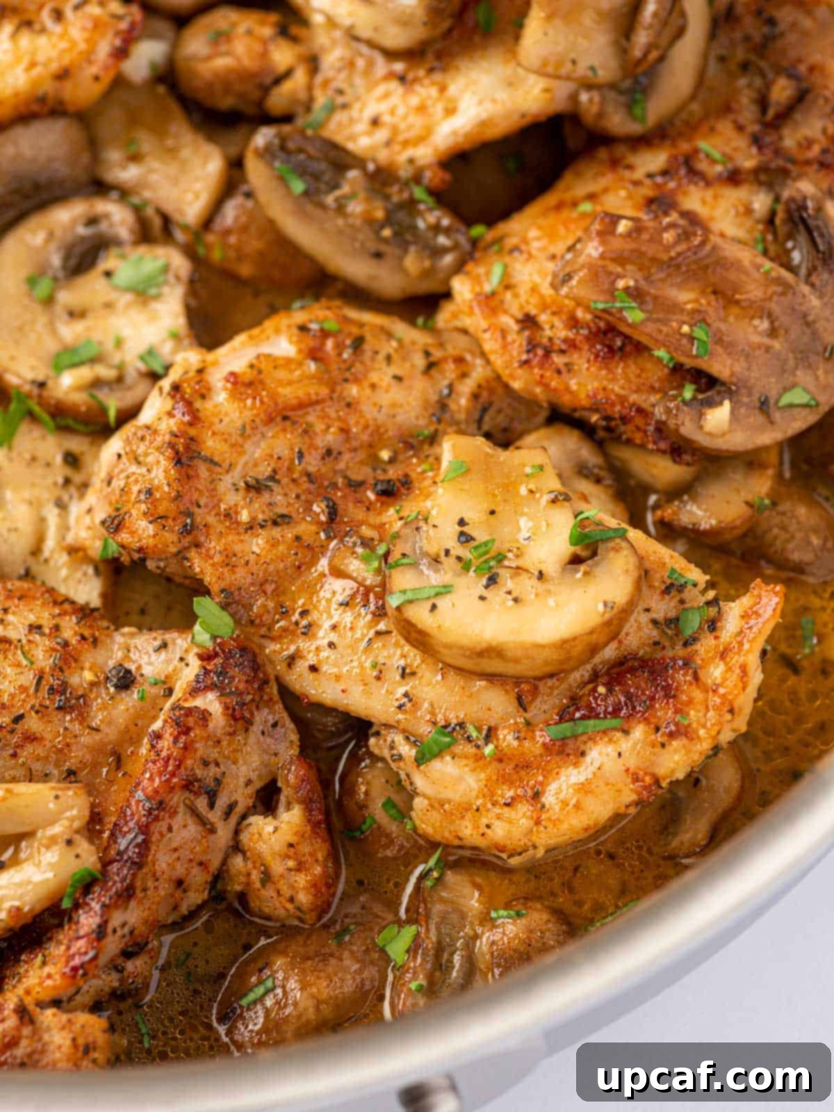 Flavorful Garlic Mushroom Chicken Thighs 8 A close-up shot of garlic mushroom chicken thighs perfectly cooked in a pan, garnished with fresh parsley.