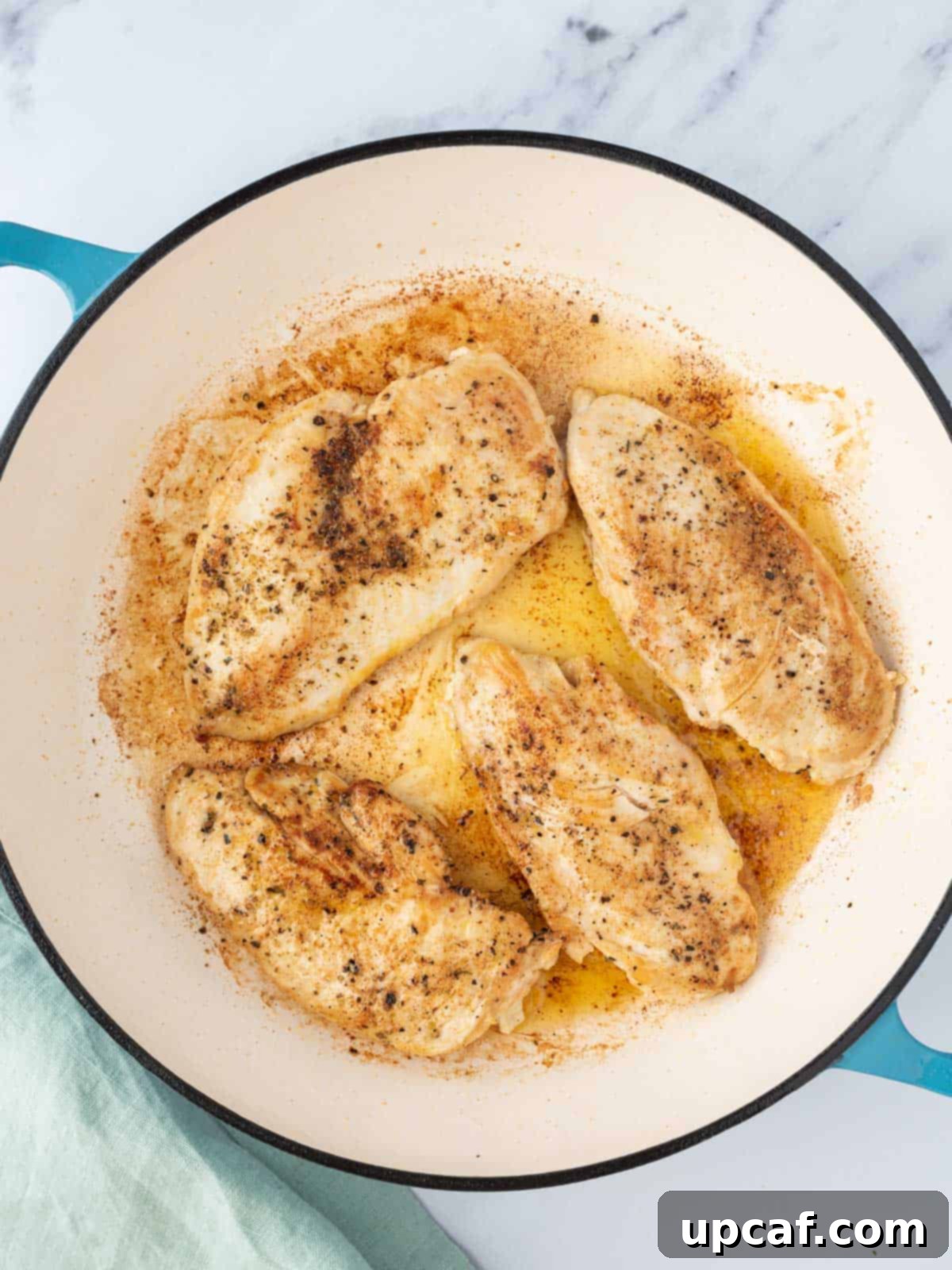 Close-up of chicken breasts searing in a hot Dutch oven with olive oil, developing a golden-brown crust.