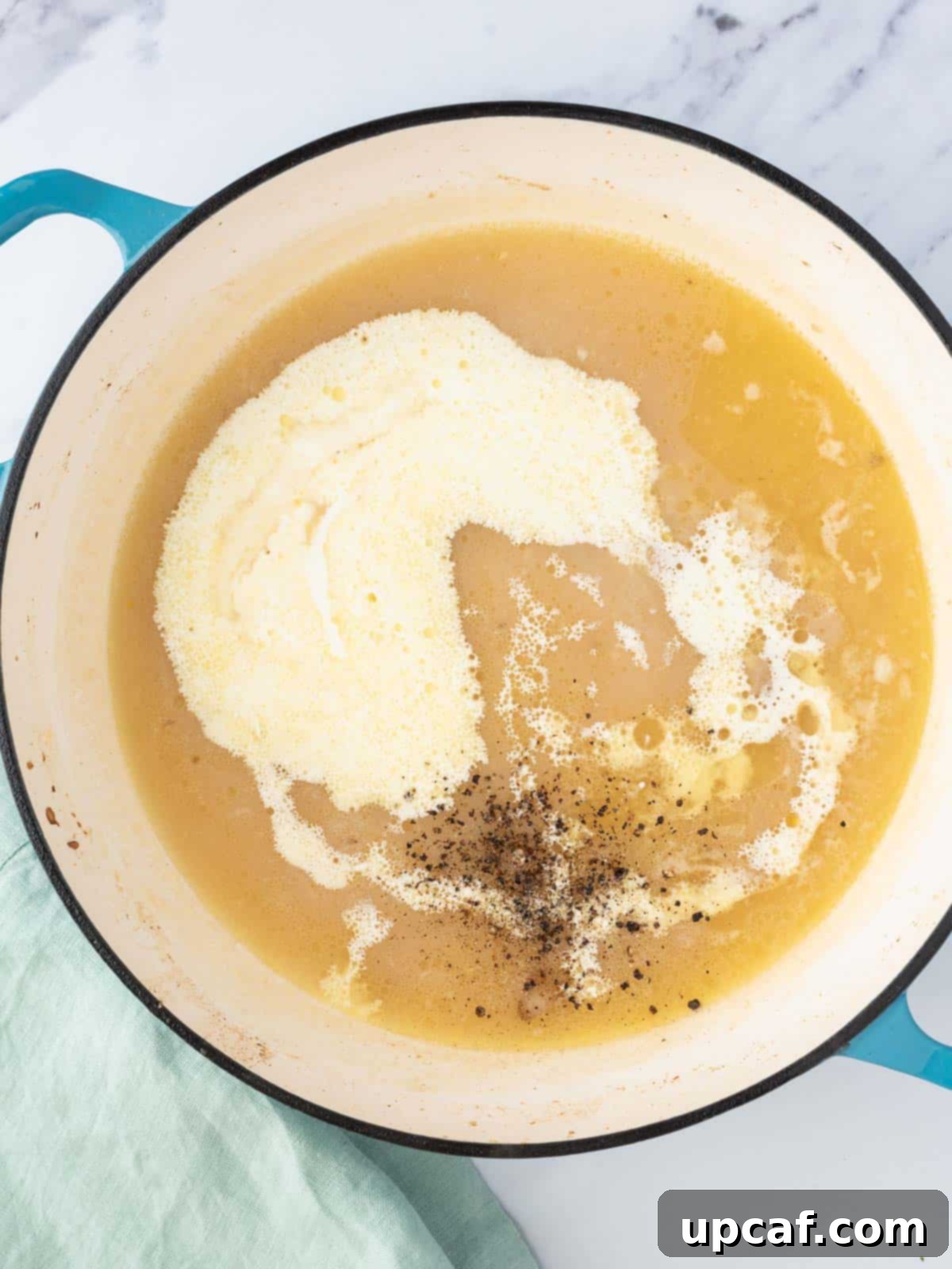 Heavy cream, salt, and pepper being added to the simmering sauce in a Dutch oven, creating a thick and creamy texture.