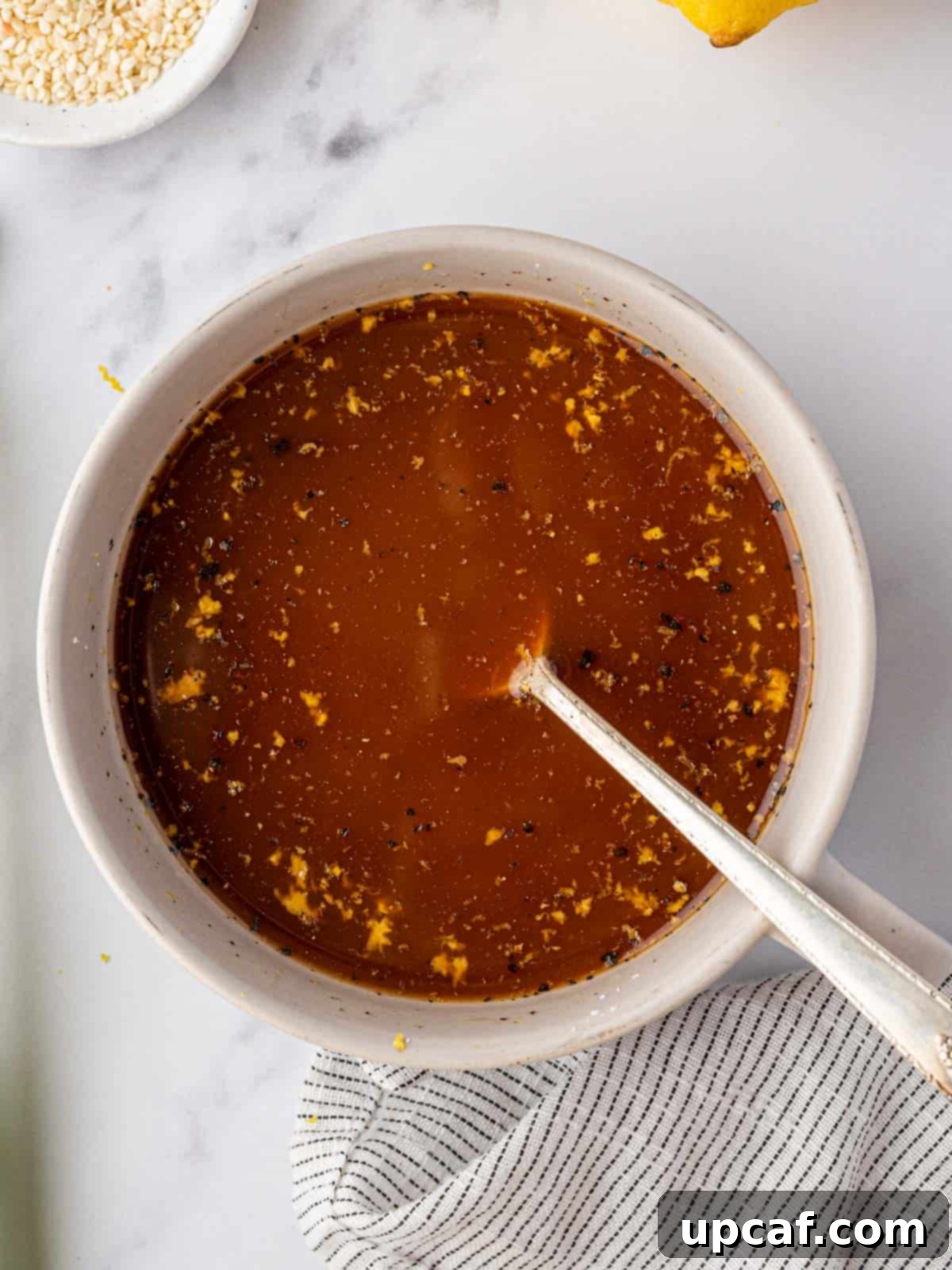 A white ceramic bowl filled with the prepared Chinese lemon sauce, with a silver spoon resting inside.