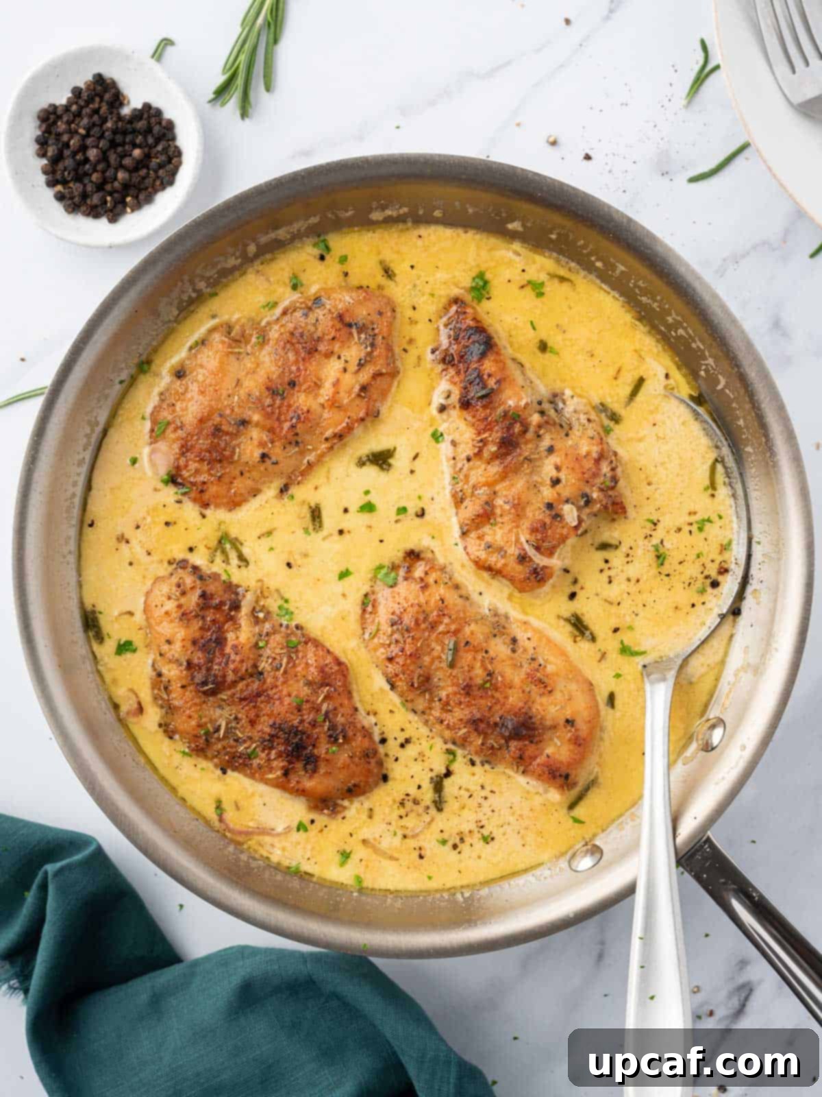 A pan of creamy mustard chicken with a serving spoon, inviting you to dig in.