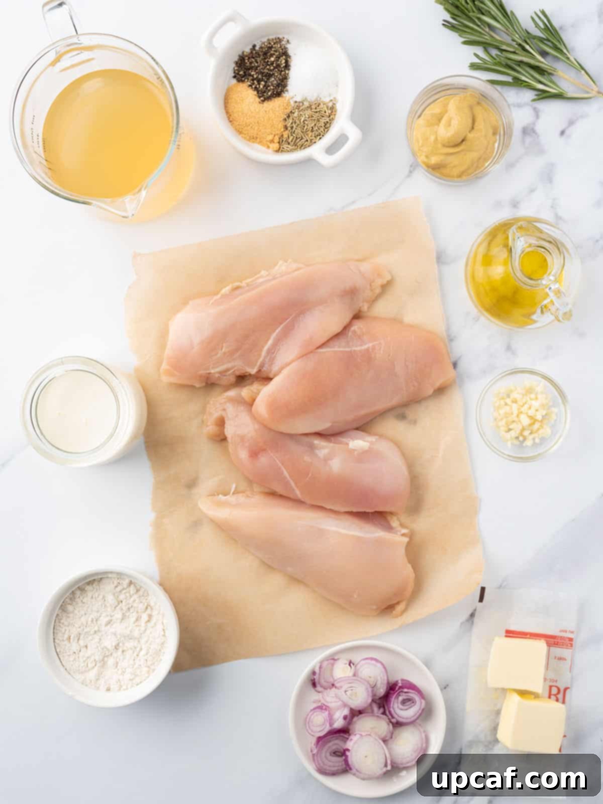 A collection of fresh ingredients laid out for making creamy mustard chicken.